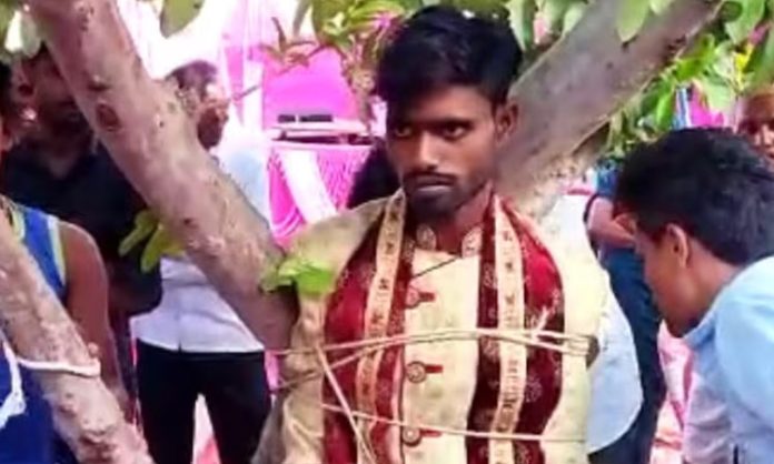 Groom tied to a tree by bride's family