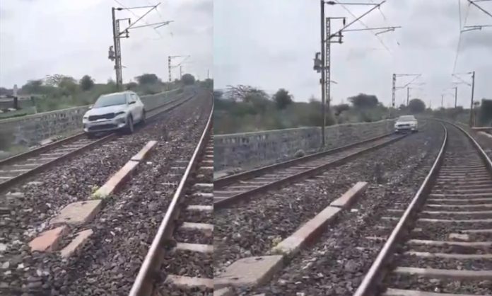 Woman drives car on railway tracks